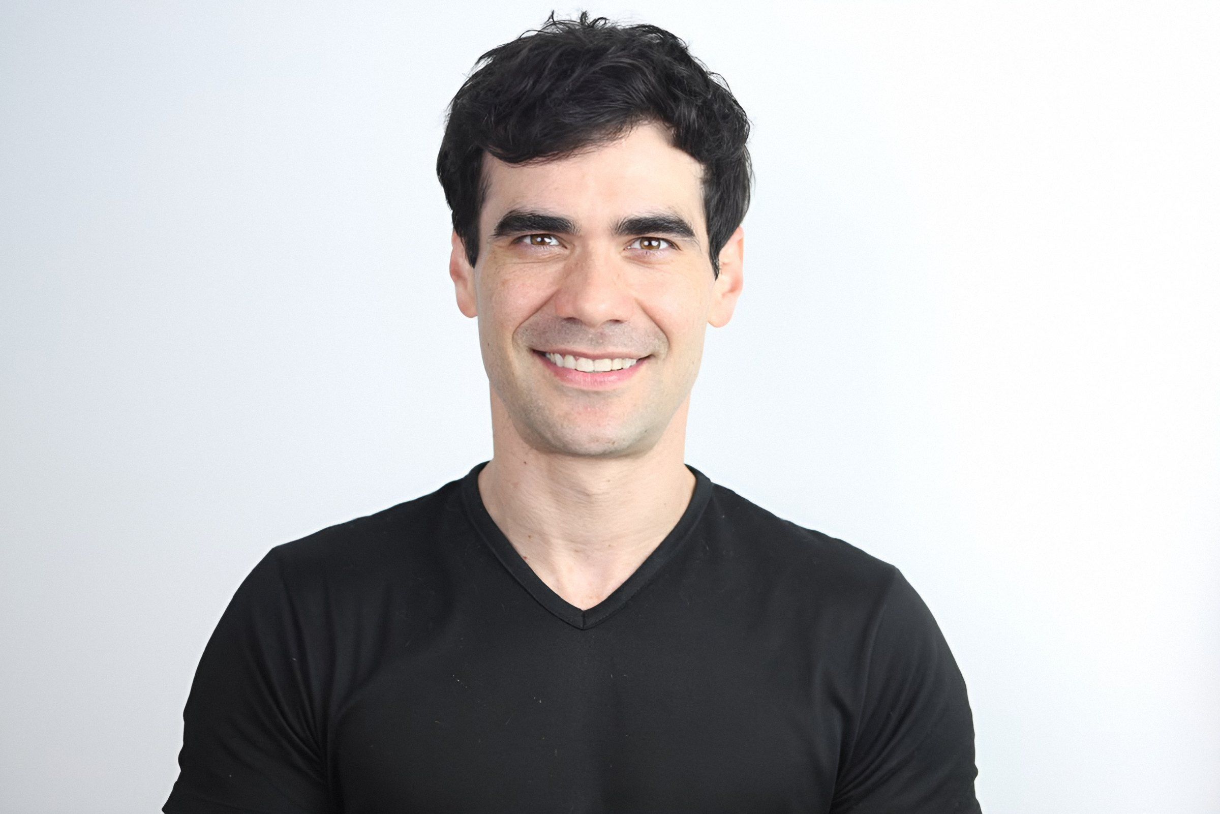 Retrato de Germán Valdés de playera negra, sonriendo de frente