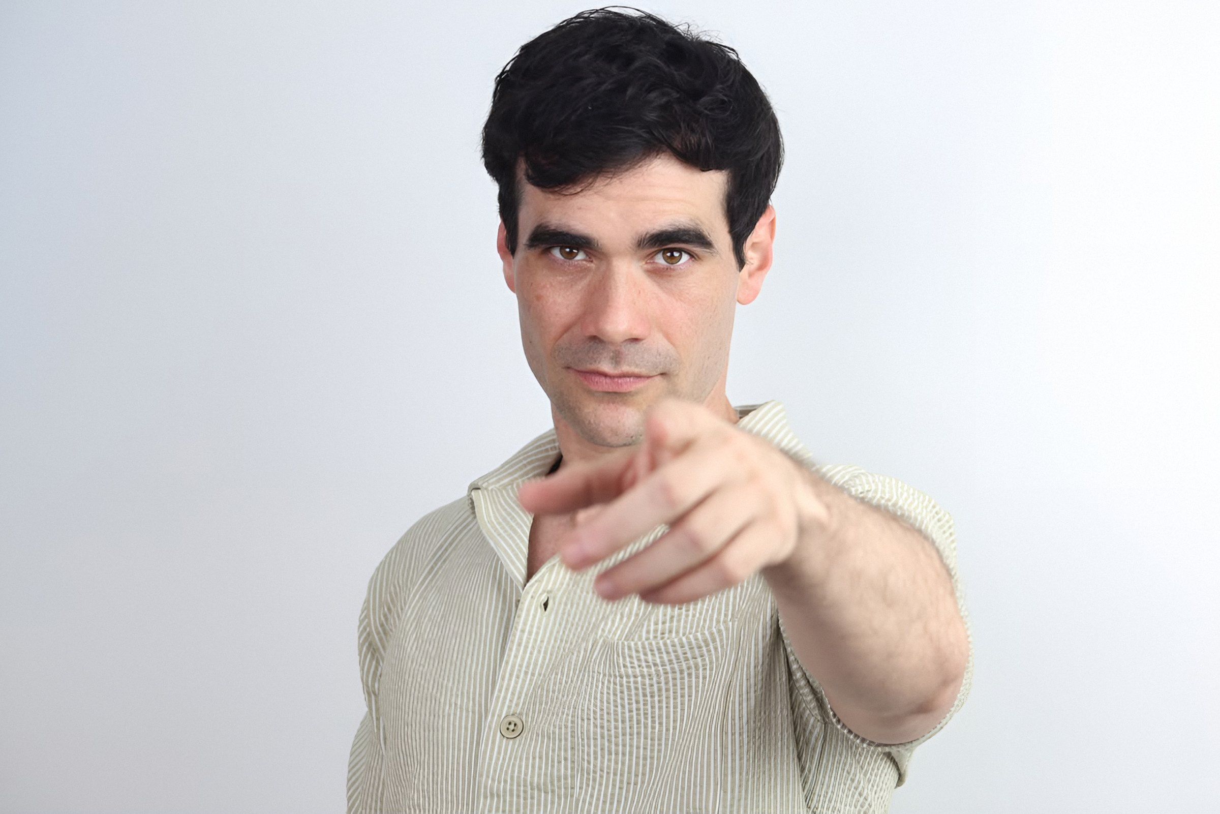 Germán Valdés con camisa beige señala a la cámara con media sonrisa