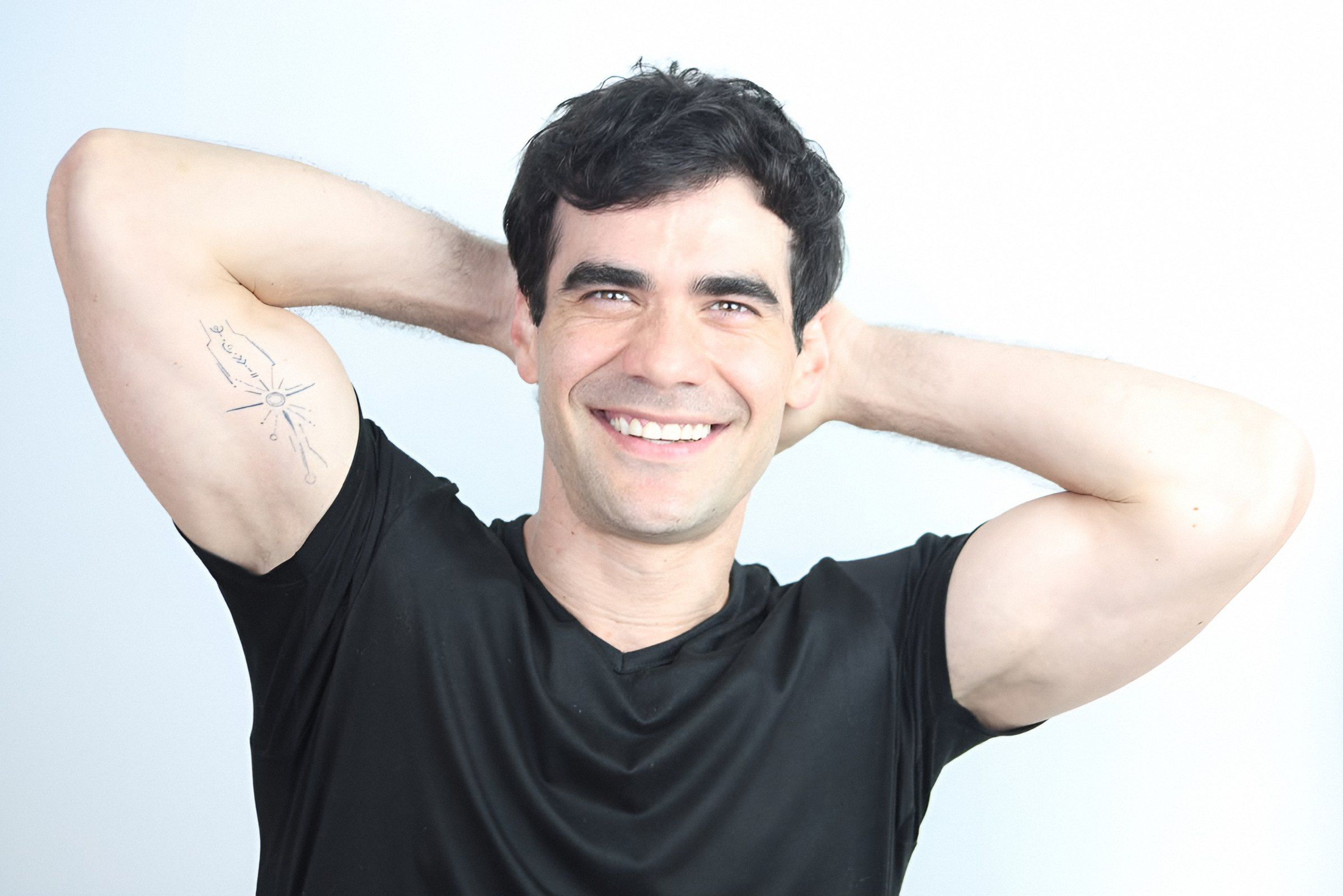 Germán Valdés de playera negra sonríe con las manos en la nuca