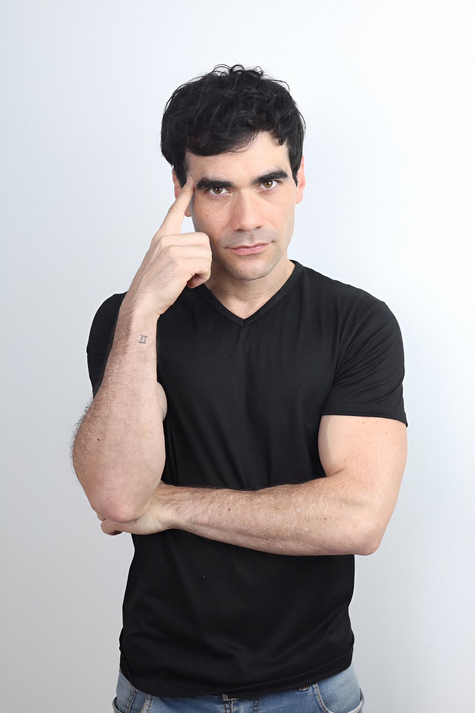Germán Valdés de playera negra, pensativo, con un dedo en la sien